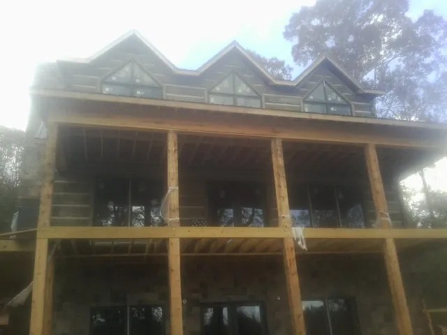 Dormers and porch framing on a large log home under construction — Roof Coating work by our crew in Sugar City